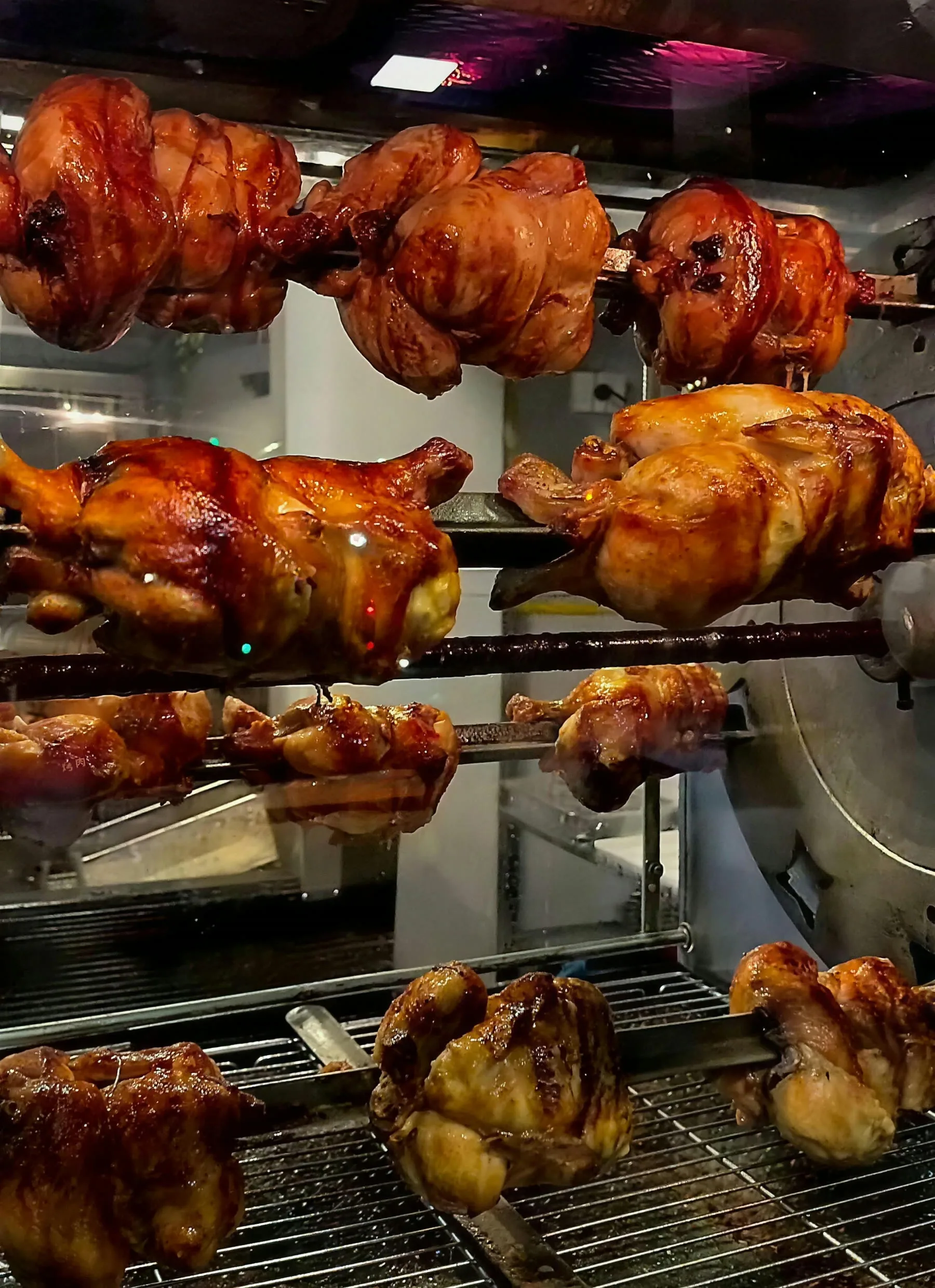 Varios pollos al spiedo girando en el asador de El Posho