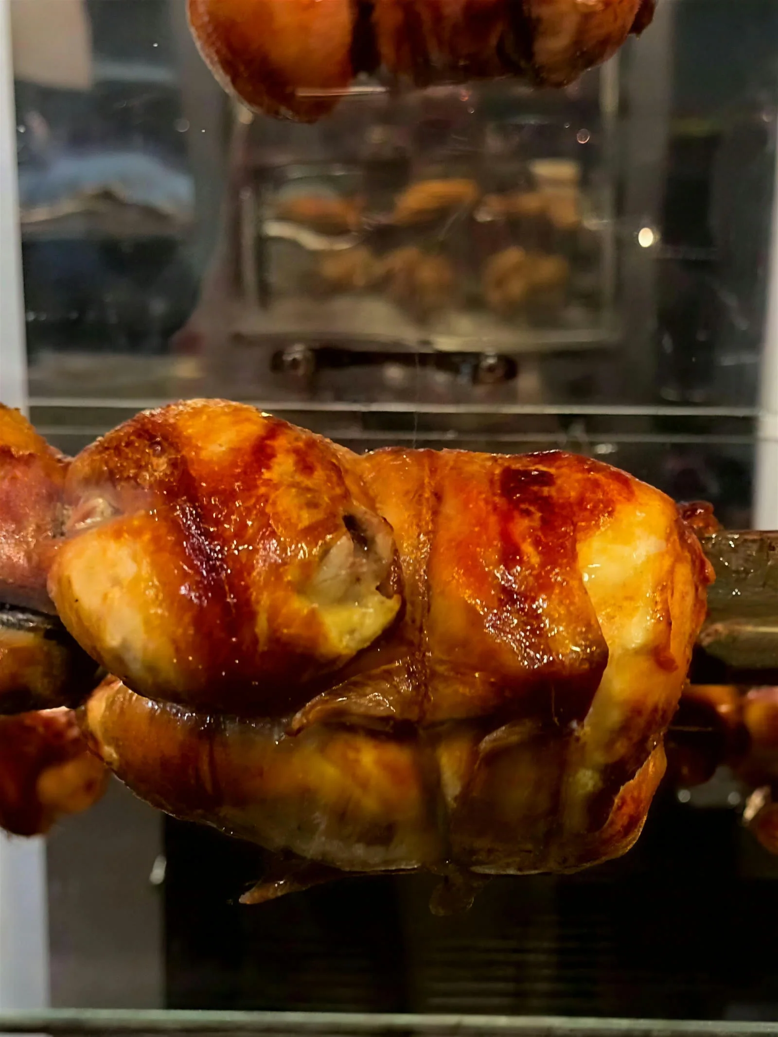 Pollo al spiedo dorado girando en el asador de El Posho